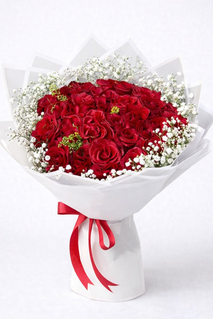 Bouquet of red roses with a white wrap and red ribbon